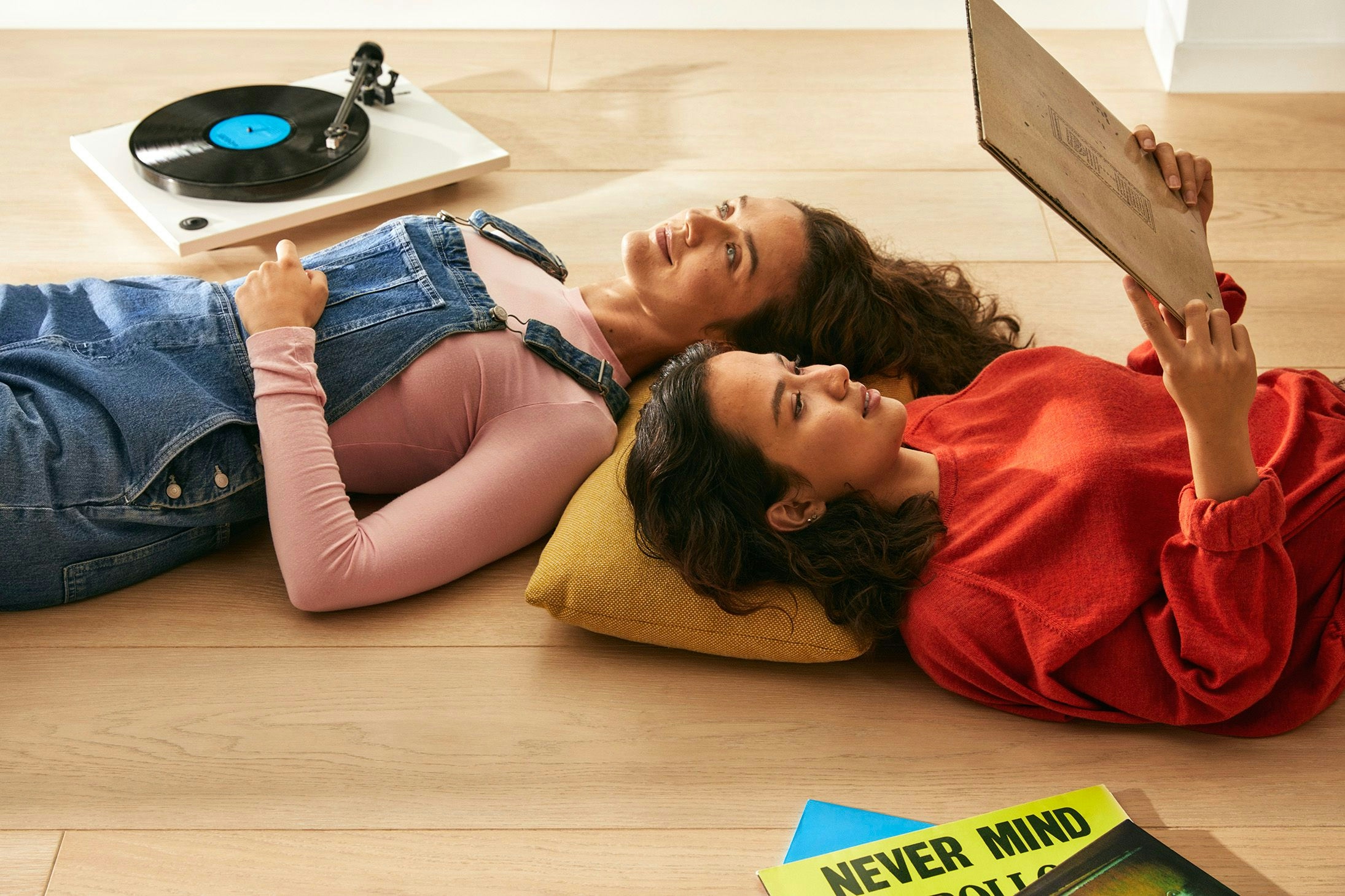 To jenter som ligger på gulvet og hører på vinylplater