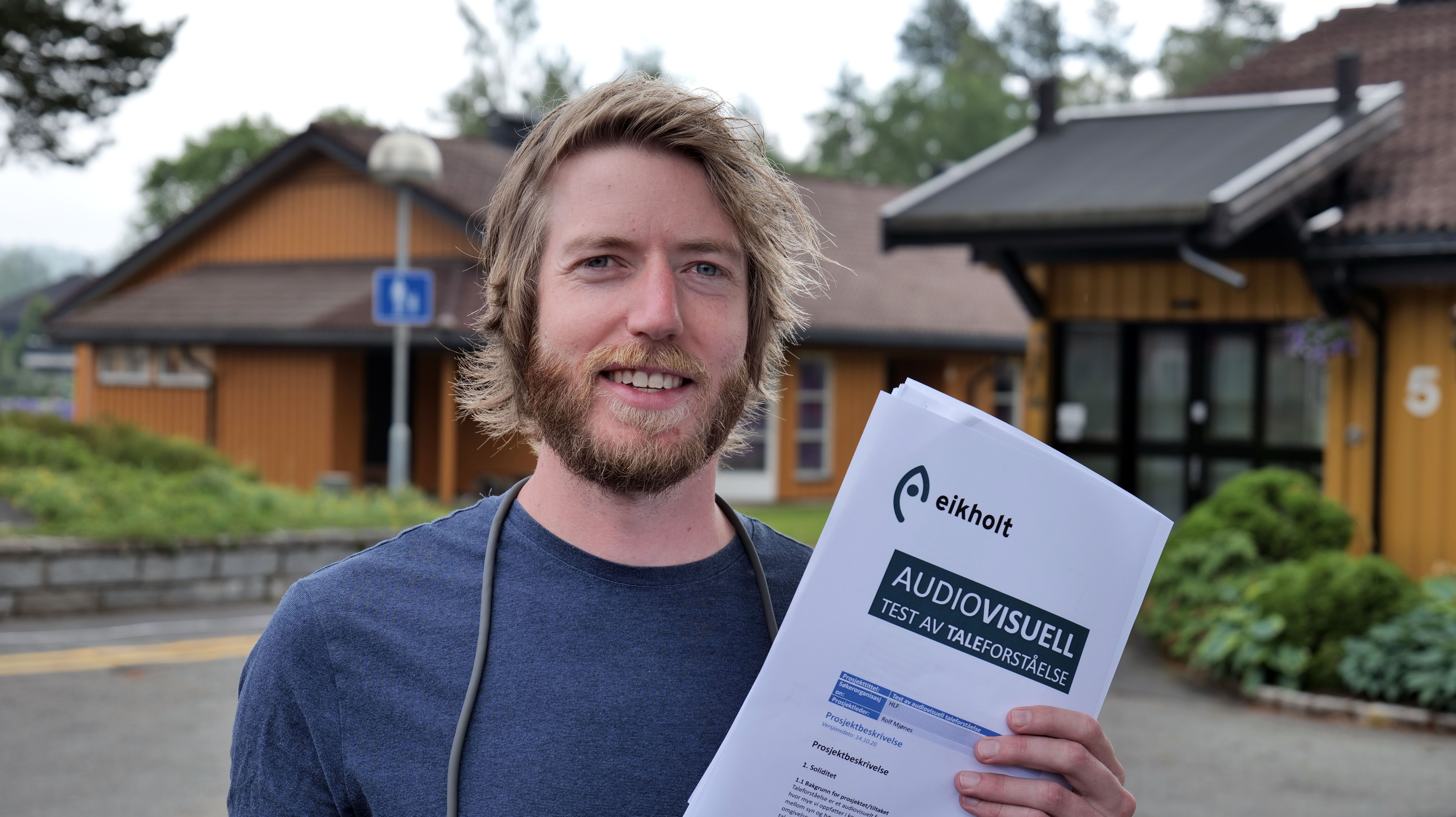 En smilende Rolf Mjønes med en rapport i hånden