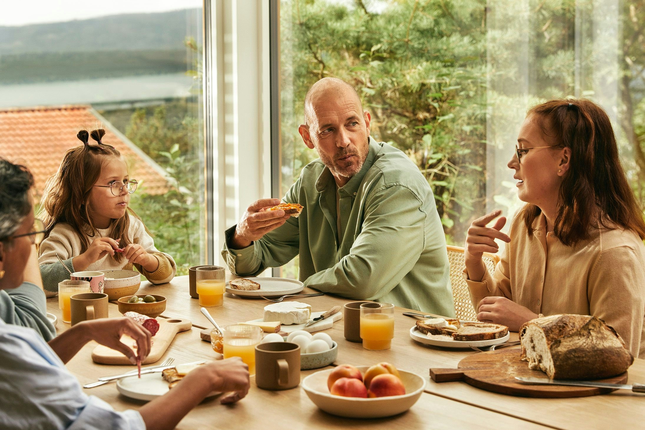 Familie sitter rundt et bord å kommuniserer og spiser mat